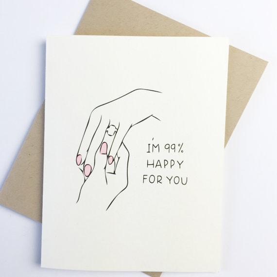 White wedding card with a drawing of two ladies hands, one with a diamond on it. with black font that says 