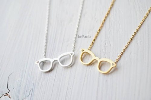 Two necklaces one silver and one gold both with glasses charms. 