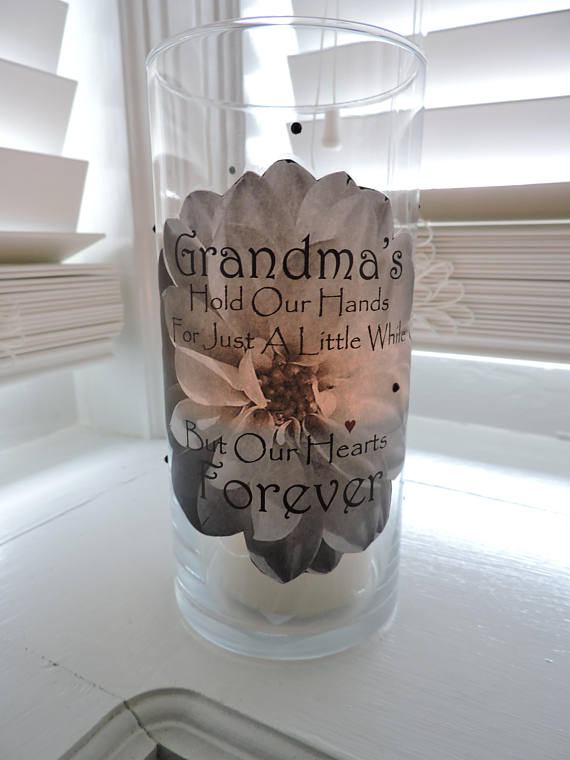 Tall clear vase with black font that says Grandma's hold our hands for just a little while, but our hearts forever and a flower inside. 