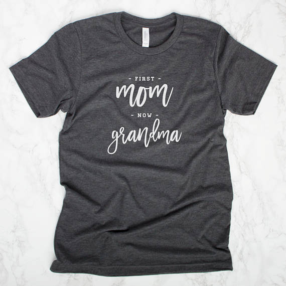 Dark Grey t-shirt with white font that says First Mom now Grandma on it. 