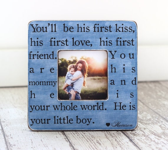 Blue square frame with a photo of a mom holding a little toddler boy with the sun setting. On the blue frame is black font that says You'll be his first kiss, his first love, his first friend. you are his mommy and he is your whole world. he is your little boy.