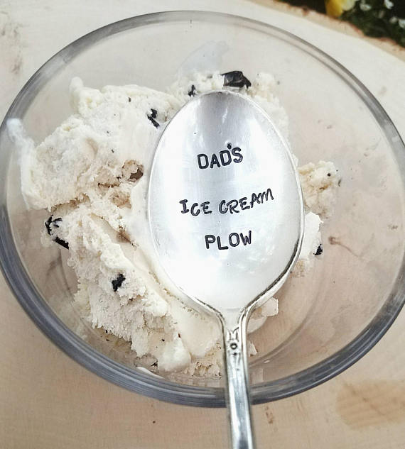 Above view of a clear bowl with cookie and cream ice cream with a spoon above it that says Dad's ice cream plow on it. 