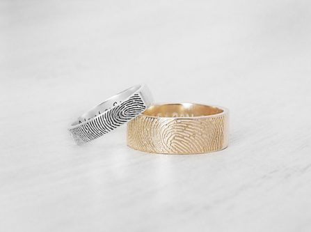 Two rings shown, one thinner silver one with a fingerprint on it and a larger gold one with a fingerprint on it. 