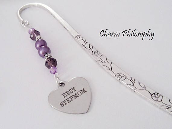 Silver thin bookmark with purple beads and a silver heart at the end with black font that says Best stepmom. 