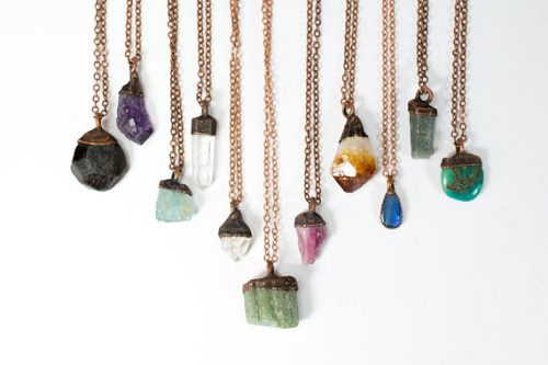 11 necklaces all with different mineral birthstones attached to the end of bronze colored chains. 