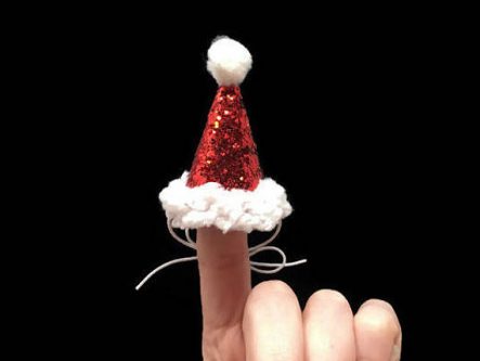 Close up of a finger with a sparkly red and white Santa hat on it. 