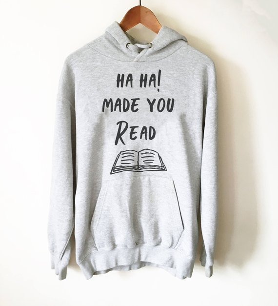 Light grey hoodie with black font that says "Ha ha! Made you read" with a cartoon open book. 