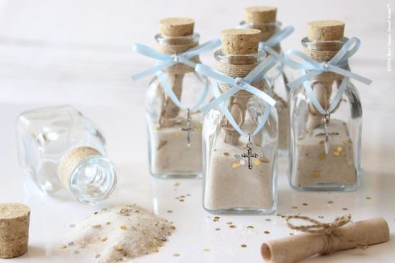 Tiny bottles with a cork top filled with sand and a cross hanging from it.