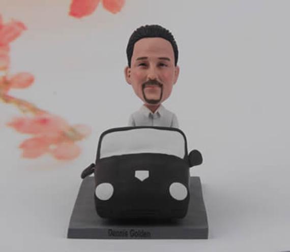 Black car with a man bobblehead figurine in it. 