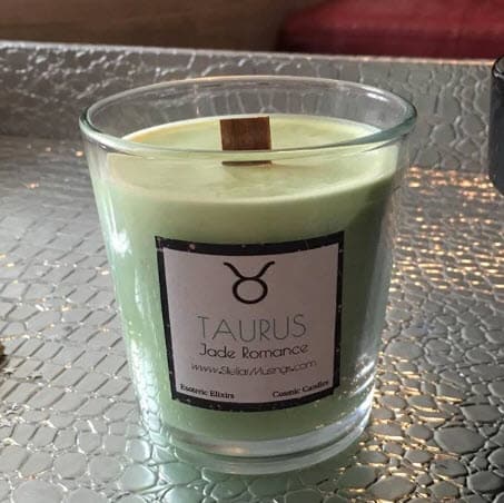 Light green candle in a clear jar with a white label on it that says Taurus.