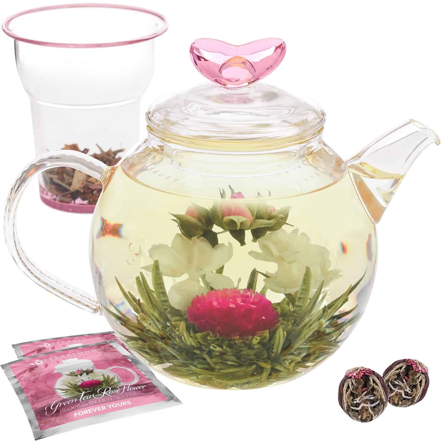 Clear teapot with pink and white flowers in it.