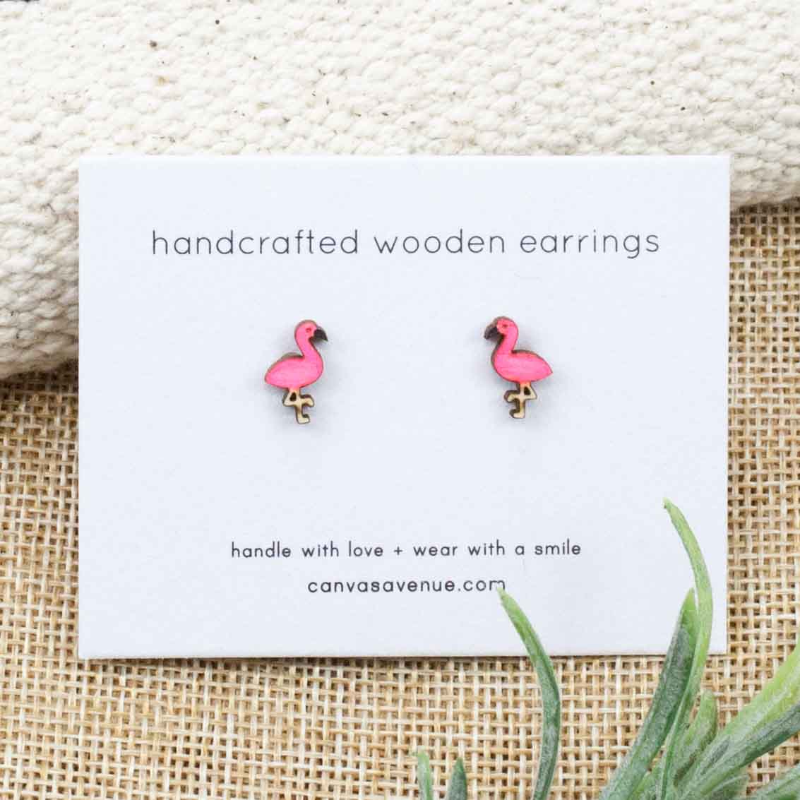 Cute stud style flamingo earrings on an earring card and sitting on a linen background