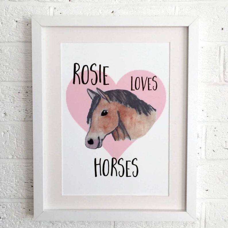 White framed drawing of a brown horse in a pink heart that says Rosie Loves horses. 