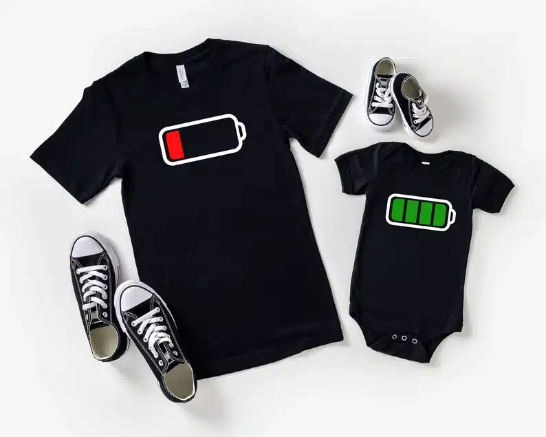 Matching daddy and baby black t-shirt and onesies with black and white sneakers beside each one. Dad one with a battery pack in the red and the baby's fully green. 