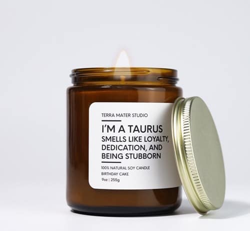 Gift Ideas for the Taurus Woman: Brown open jar with a gold lid leaning on it. White label with black font that says "I'm a Taurus smells like loyalty, dedication, and being stubborn".