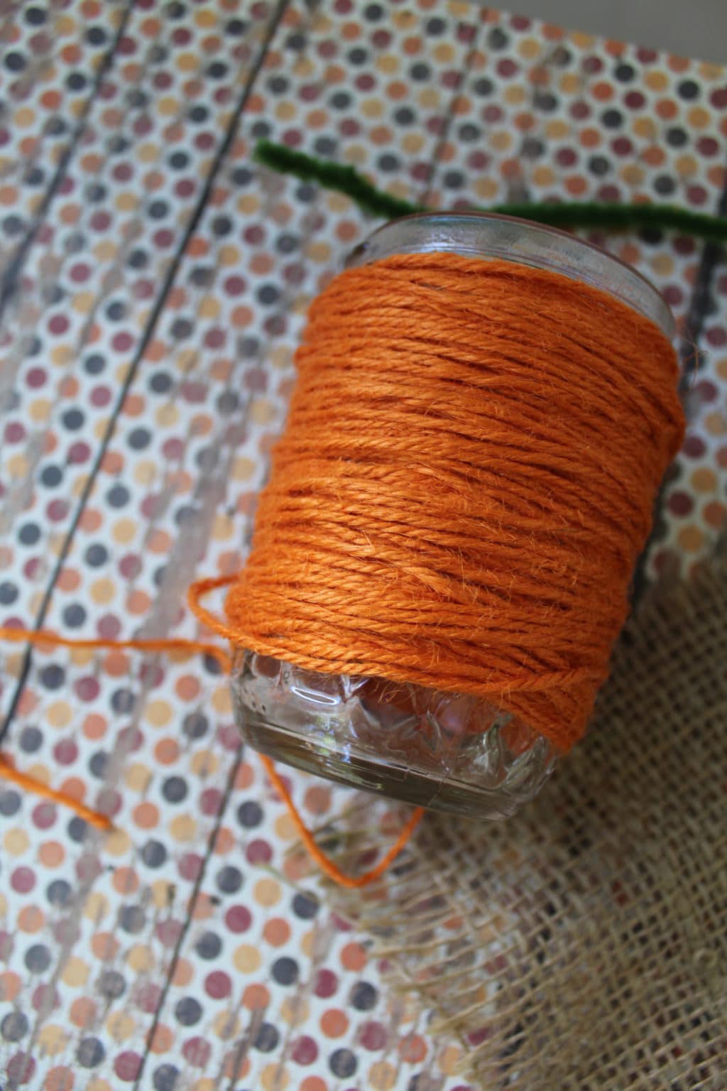 Glass jar on its side showing a close up of orange twine. 