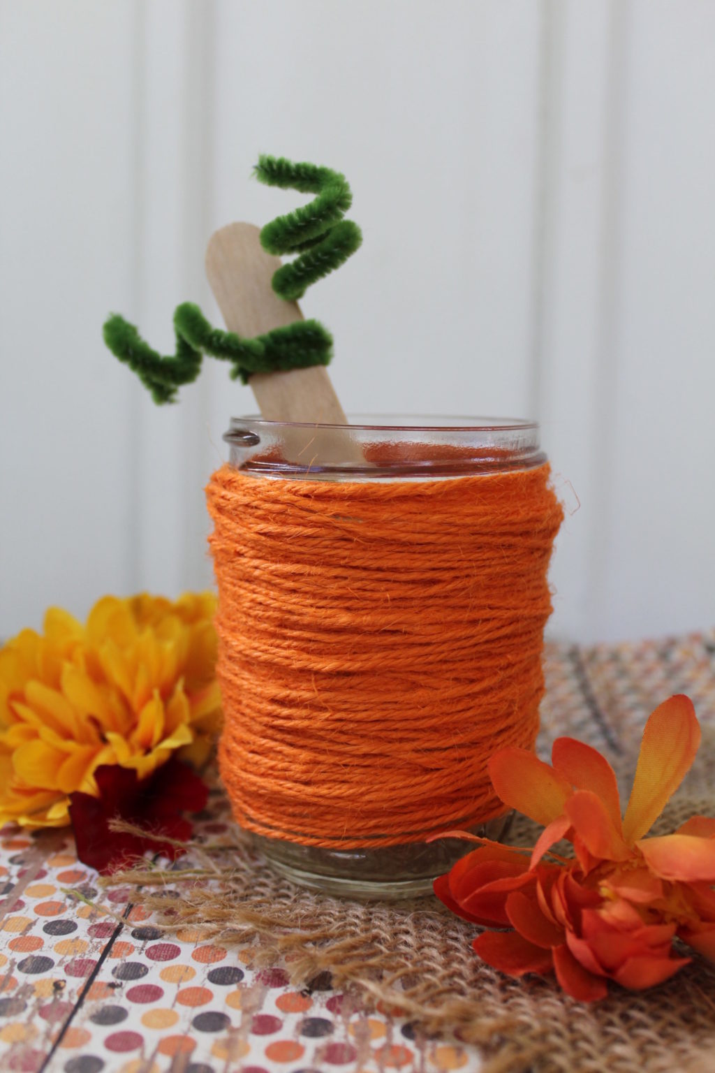 Completed pumpkin jar with fake flowers in background. 