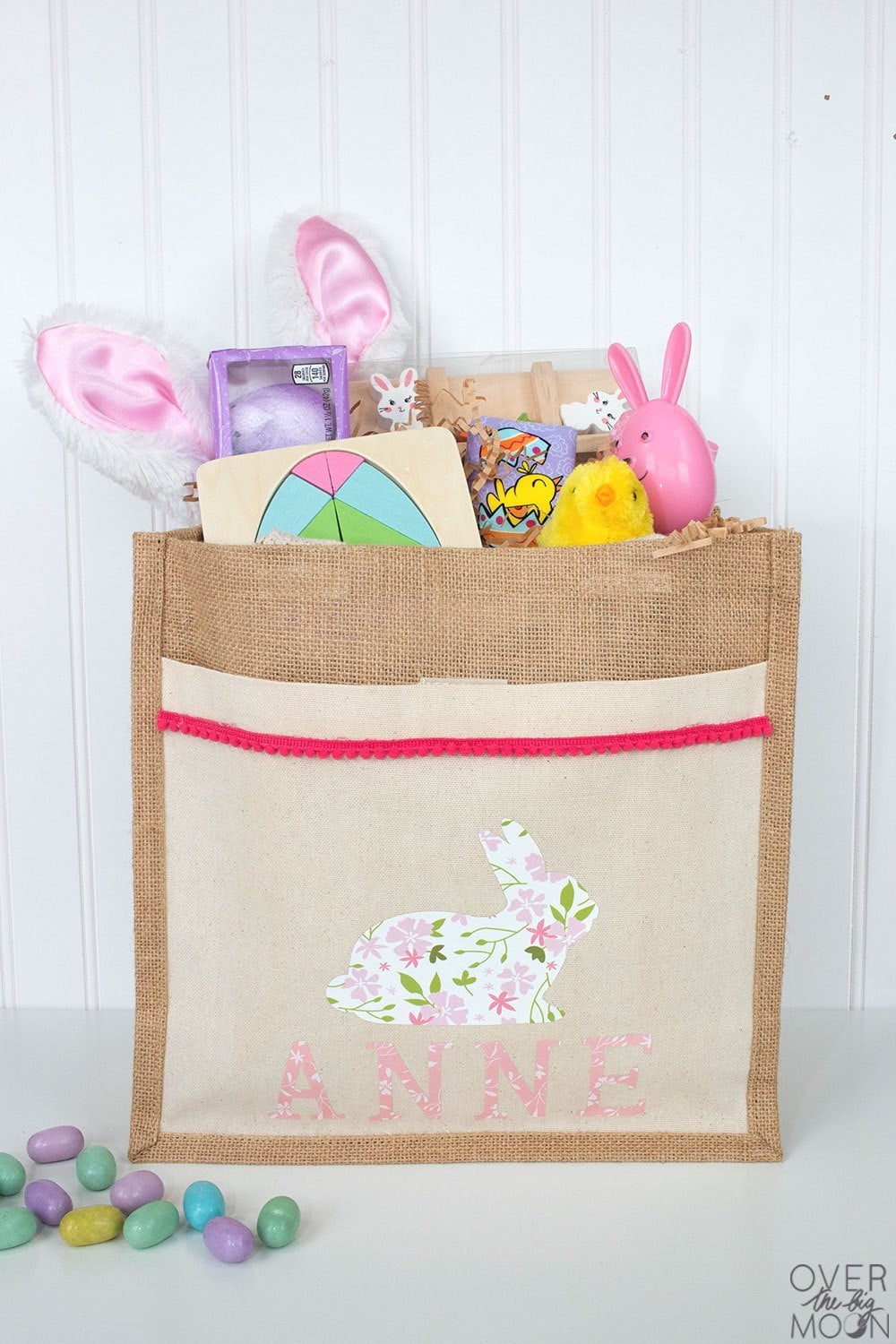 pouch style bag made of burlap with iron on print of white bunny with pink flowers with the name ANNE below it. 