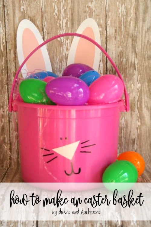 Pink plastic bucket with bunny face drawn on it and filled with colorful Easter eggs. 