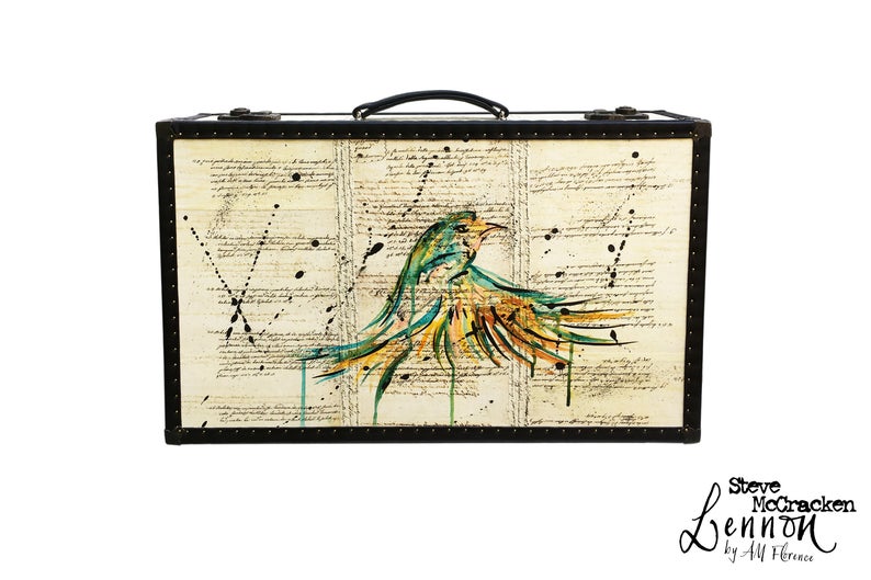 Vintage style suitcase with old paper written stuff all over and a painted bird on it. 