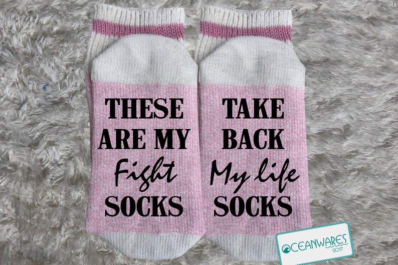 Light pink socks with white tips that says in black font on one "These are my fight socks" and on the other sock it says "take back my life socks".