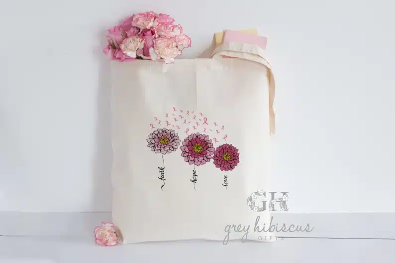 Tan tote bag with three pink flowers on it. 