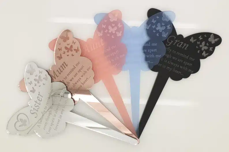 Five different butterfly memorial sticks, white, tan, pink, blue, and black. 