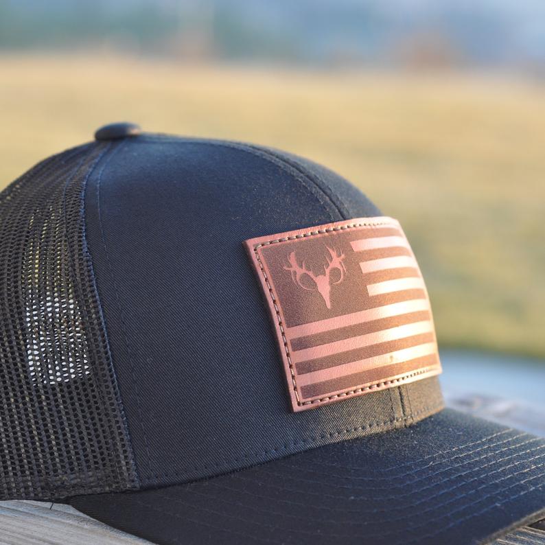 Dark grey with mesh back baseball hat with an American flag with a deer head in the place of the stars. 
