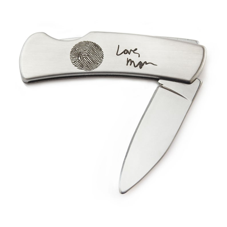 Silver pocket knife opened, finger print on it that says Love mom beside it. 