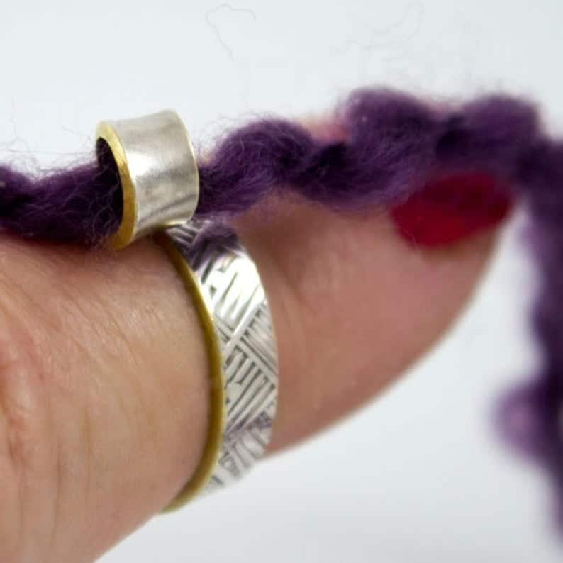 Finger with a crochet ring on it with purple yarn in it.