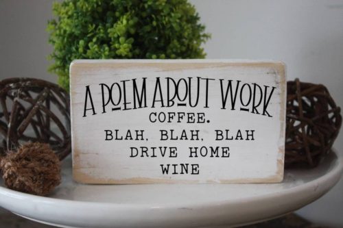 Funny wooden desk sign that reads: A poem about work, coffee. blah, blah, blah Drive home wine. In black font. 