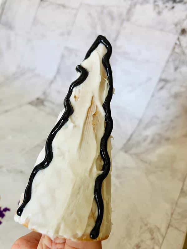 applying black icing to a sweet Halloween ice cream cone treat craft