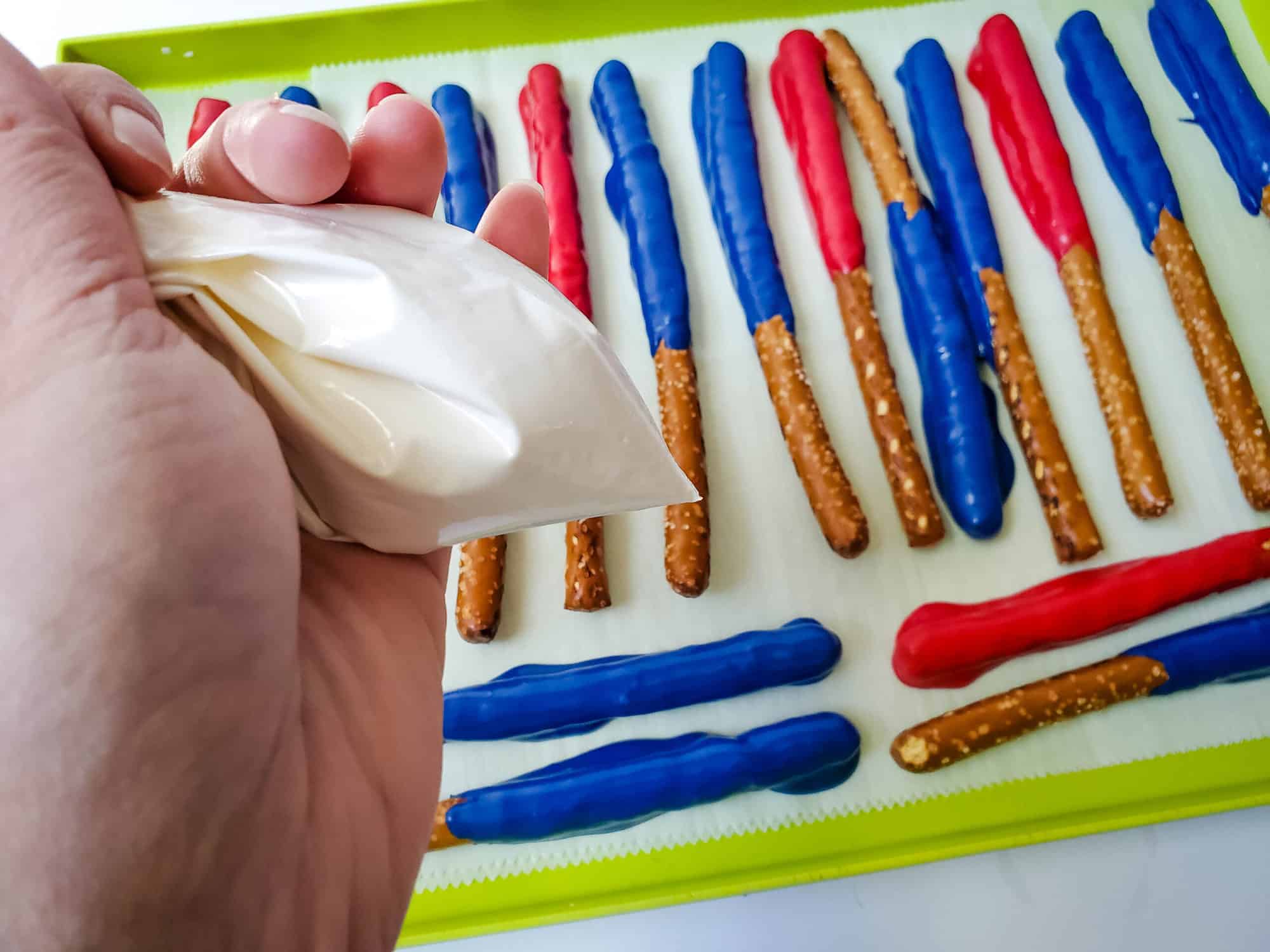 chocolate coated pretzel rods arranged on a a baking pan with parchment paper