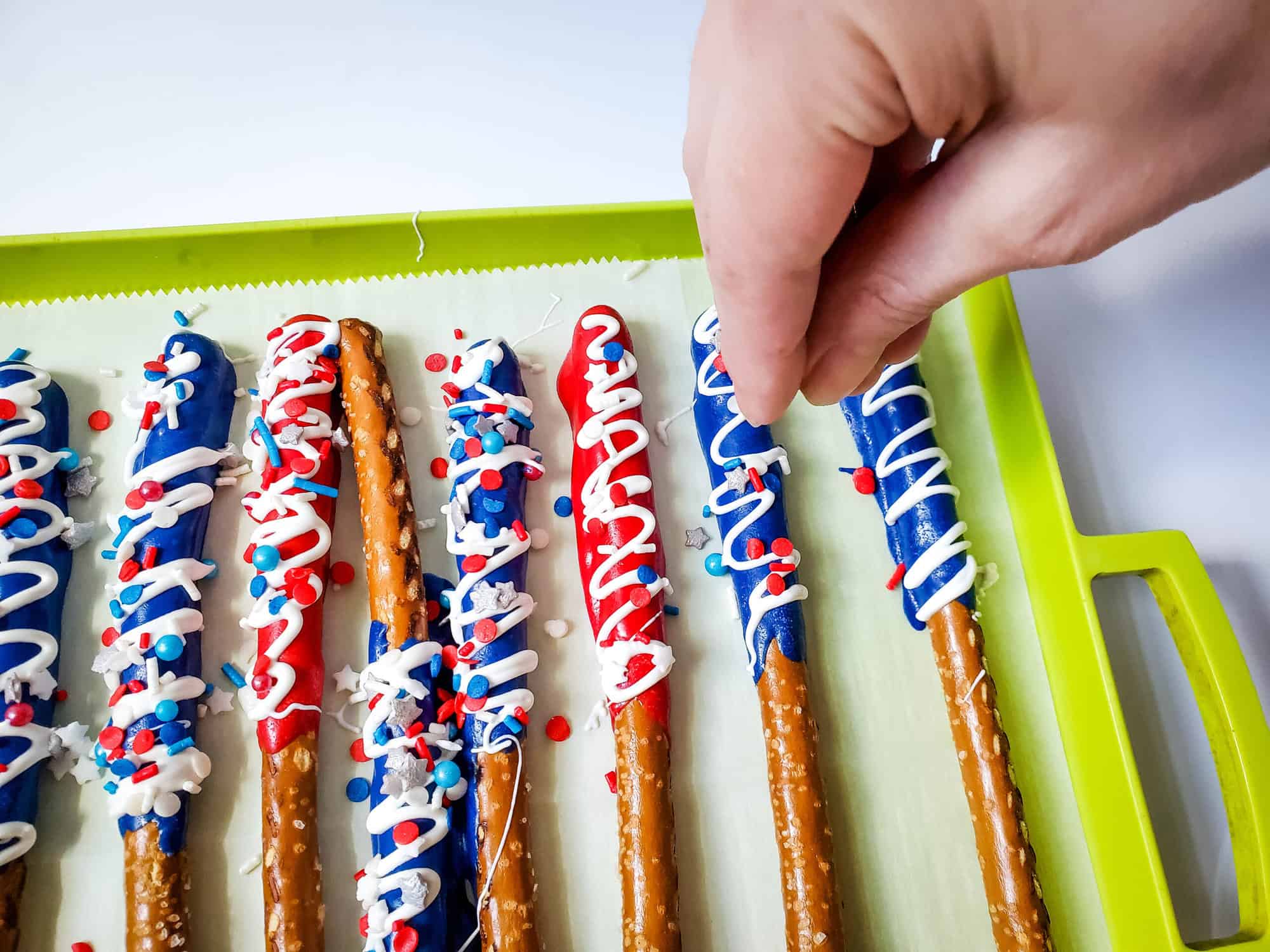 topping patriotic pretzel rods with sprinkles