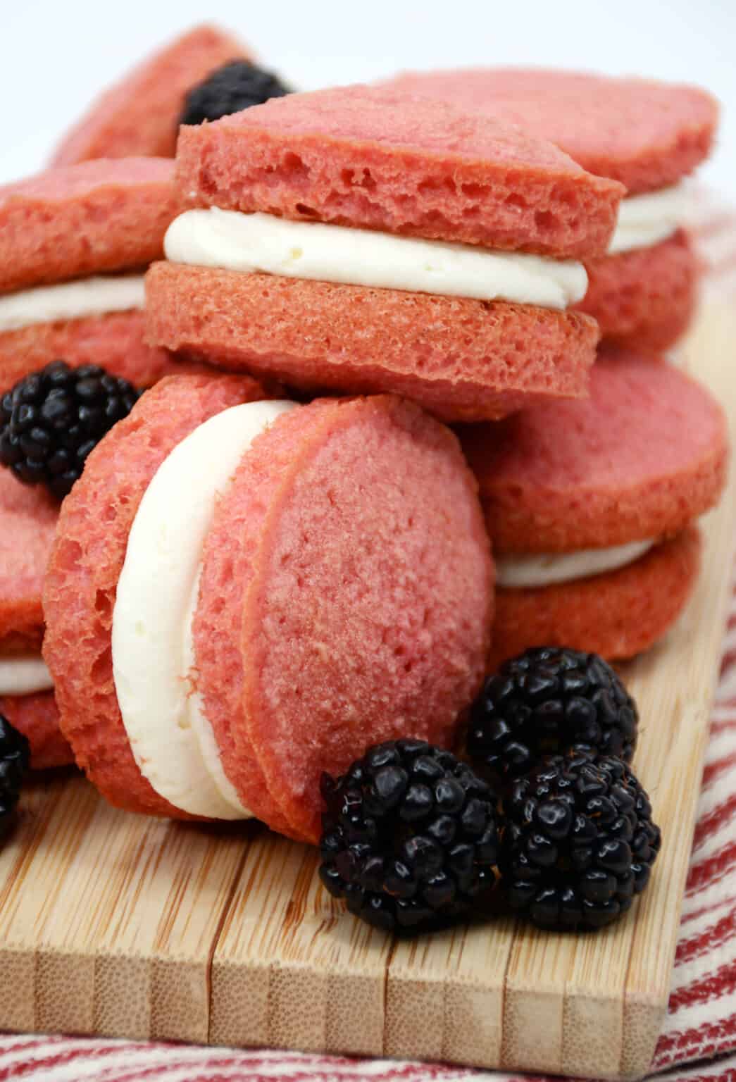 showing various whoopie pies with cream cheese icing and full fresh blackberries around it. 