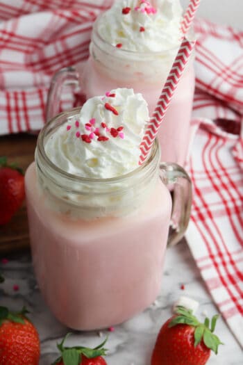 front view of strawberry hot chocolate with full fresh strawberry scattered around it.