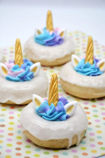 completed unicorn donuts with light blue and purple frosting in the donut hole, with ears and gold horn.