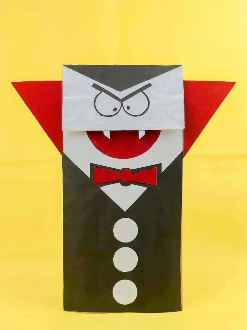 Dracula paper puppet craft for kids in front of a yellow backdrop