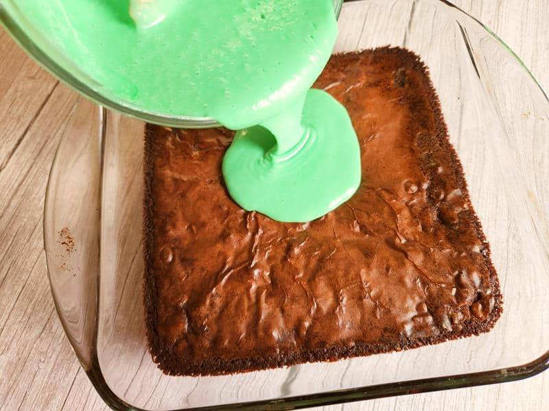 pouring green frosting on brownies