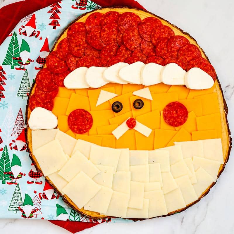 smiling santa Christmas charcuterie board idea with festive decorations