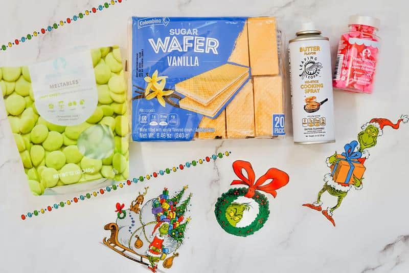 ingridients for making Grinch wafer cookies with wafers, meltable icing, butter spray and sprinkles