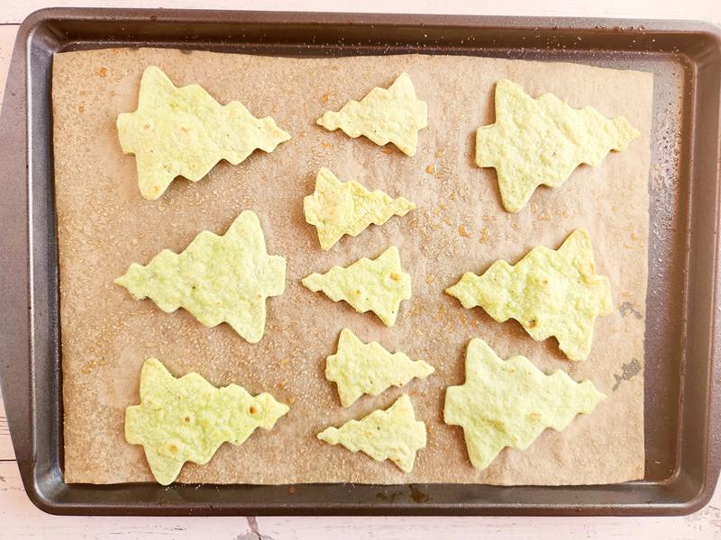 Baking sheet with baked homemade tortilla chips shaped like Christmas trees