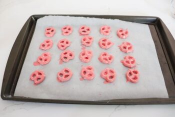 baking sheet with 20 pretzels covered in candy melts. 