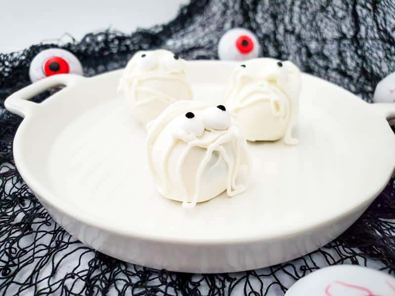 close up of Oreo mummy balls covered in white chocolate, piped chocolate and candy eyes. 