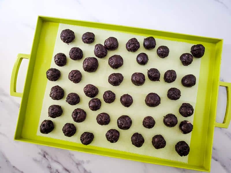 Lime green baking sheet with parchment paper and rolled Oreo balls. 