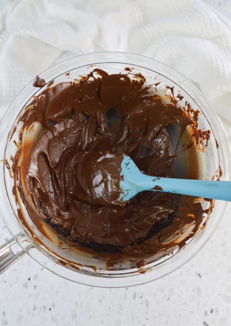 showing bowl of melted chocolate with blue spatula in bowl. 