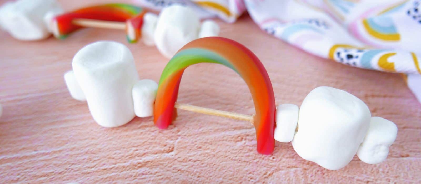Rainbow Skewer Snacks, showing bamboo skewer with marshmallows and rainbow candy arched like a rainbow. 
