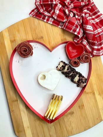 Large heart shaped box being filled with brie cheese, heart shaped container, one rose meat.