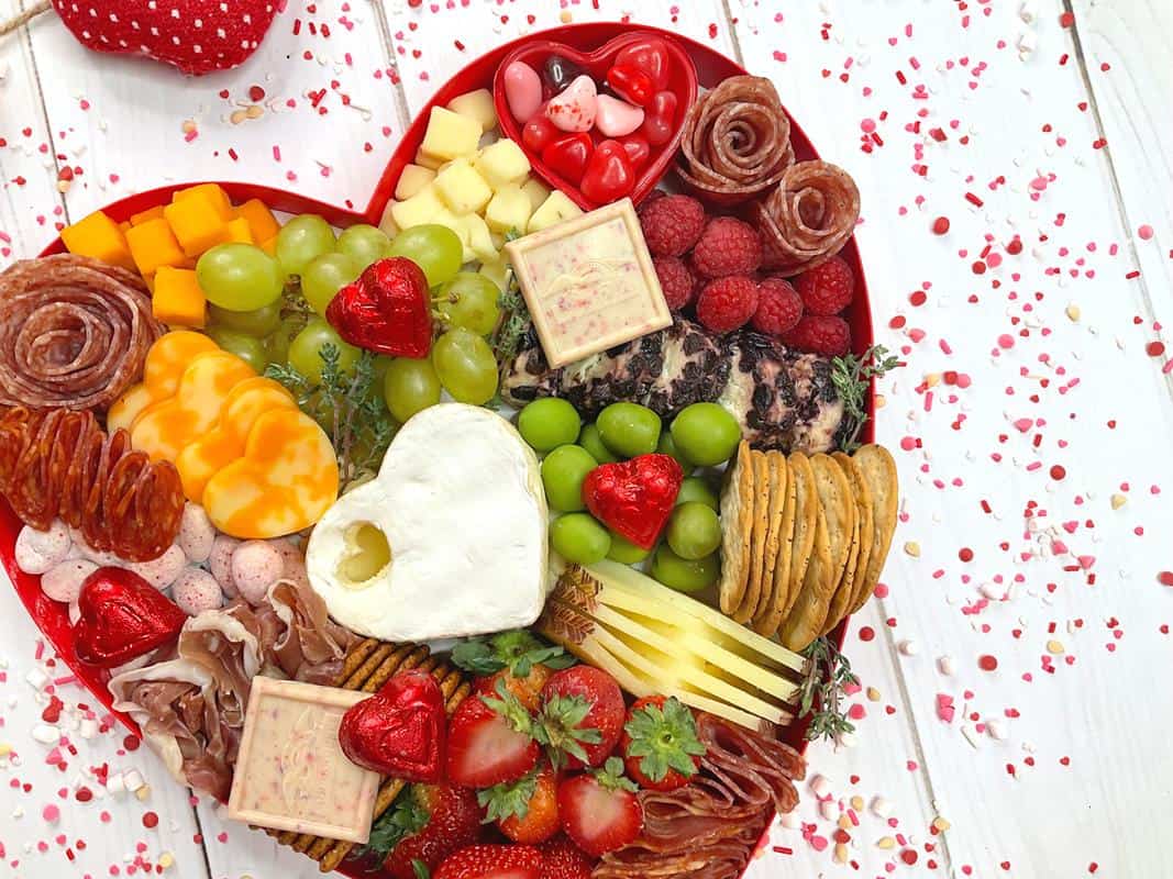 meat shaped into roses, cheese into hearts and various fruit, crackers, chocolates in a heart shaped box.