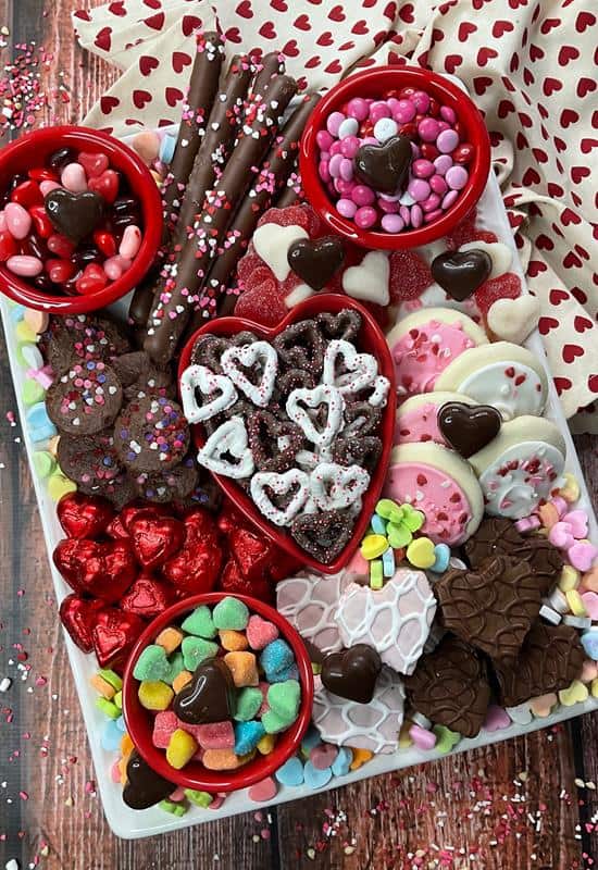 above view of Valentine snack board with various heart shaped baked goods, candies, and pretzels. 